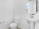 Clean half bath featuring a pedestal sink, toilet and round mirror at 1138 Olivine Ave, Dundee, FL 33838