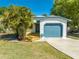 Charming home with a light blue garage door, front deck, and lush landscaping at 1211 Shawnee Dr, Kissimmee, FL 34744