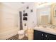 Well-lit bathroom featuring a shower-tub combo, coordinated black and white accents, and ample storage at 133 Rona Ln, Davenport, FL 33897