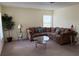 Bright living room with neutral carpet, brown sectional sofa, coffee table and a houseplant by the window at 133 Rona Ln, Davenport, FL 33897