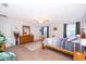 Bright main bedroom with a wood bed, neutral carpet, ceiling fan, and sitting chair at 133 Rona Ln, Davenport, FL 33897