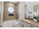 Modern bathroom featuring a patterned wall, soaking tub, round window, and marble countertops at 1436 Stetson St, Orlando, FL 32804