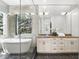 Modern bathroom featuring a soaking tub, glass shower, marble countertops, and white cabinetry at 1436 Stetson St, Orlando, FL 32804