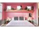 Charming bedroom with unique pink walls, wooden accents, and live plants above the bed at 1672 Tropical Palms Cir, Kissimmee, FL 34747