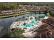 Aerial view of a resort-style pool with palm trees and lounge chairs surrounded by community residences and a lake at 2621 Corvette Lane, Kissimmee, FL 34746
