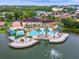 Aerial view of a resort-style pool, hot tub, and sun deck with community residences surrounded by a lake and green space at 2621 Corvette Lane, Kissimmee, FL 34746