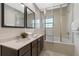 Bathroom featuring double sinks, modern faucets, large mirrors, and a shower with tub at 2621 Corvette Lane, Kissimmee, FL 34746