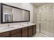 Well-lit bathroom showcasing double sinks with modern fixtures and glass-enclosed shower stall at 2621 Corvette Lane, Kissimmee, FL 34746