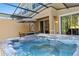 Inviting hot tub offers relaxation within the screened patio, complemented by an umbrella covered table at 2621 Corvette Lane, Kissimmee, FL 34746