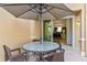 Covered patio with round table, chairs, umbrella, and sliding glass doors leading indoors at 2621 Corvette Lane, Kissimmee, FL 34746