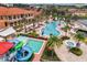 Aerial view of a resort-style pool area including a water slide, hot tub, palm trees, and lounge chairs for community residents at 2621 Corvette Lane, Kissimmee, FL 34746
