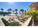 Enjoy the spacious pool area with palm trees, lounge chairs, umbrellas, and clear blue water on a sunny day at 2621 Corvette Lane, Kissimmee, FL 34746