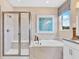 Bright bathroom featuring a soaking tub, glass-enclosed shower, and elegant marble-style tile at 280 Hilltop Bloom Loop, Haines City, FL 33844