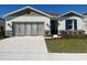 Charming single-story home featuring a stone-accented facade, well-manicured lawn, and concrete driveway at 280 Hilltop Bloom Loop, Haines City, FL 33844