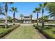 Inviting community entrance with lush landscaping and a covered entry, flanked by palm trees under a bright blue sky at 2920 Windmill Dr, Kissimmee, FL 34741