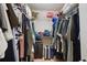 This is a walk-in closet with metal shelves, hanging clothes and a hard suitcase on the floor at 2920 Windmill Dr, Kissimmee, FL 34741