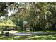 A concrete basketball court with a hoop is surrounded by mature trees and benches for relaxing at 2921 Puerta Del Sol Blvd, Kissimmee, FL 34744