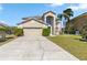 Two-story home with a two car garage, arched window, palm tree, and green door at 417 Spice Ct, Kissimmee, FL 34758