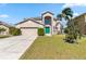 Two-story home with a two car garage, arched window, palm tree, and green door at 417 Spice Ct, Kissimmee, FL 34758