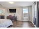 Bright bedroom with hardwood floors, a dresser with a mounted TV, and natural light from the window at 624 Sardinia Circle, Davenport, FL 33837