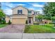 Two-story home featuring a well-maintained lawn, brick driveway, and an attached two-car garage at 624 Sardinia Circle, Davenport, FL 33837