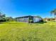 Exterior rear view of home featuring a spacious lawn area and a large screened porch with ample space for outdoor living at 657 Shorehaven Dr, Poinciana, FL 34759