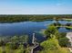 Expansive aerial view featuring a lake with a dock, lush greenery, and condo buildings in the distance at 6659 Times Square Ave 38-103 # Orlando, Orlando, FL 32835