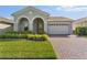 Charming home featuring manicured lawn, brick driveway, and welcoming arched entryway at 7465 Wing Span Way, Harmony, FL 34773