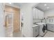 Well-equipped laundry room with modern washer and dryer, sink, cabinets, and a peek into the bathroom at 7465 Wing Span Way, Harmony, FL 34773