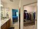 Bathroom featuring double sinks, wooden cabinets, and an open doorway to the bedroom and walk-in closet at 813 Marcel Loop, Davenport, FL 33837