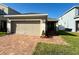 Charming one-story home featuring a two-car garage, a brick-paved driveway, and a well-maintained front yard at 813 Marcel Loop, Davenport, FL 33837