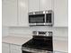 Close up of stainless steel microwave and range with white cabinets and quartz countertops at 1027 Wisteria Way, Dundee, FL 33838