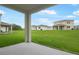 A house backyard with manicured lawn and a covered patio with support beams at 1031 Wisteria Way, Dundee, FL 33838