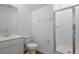 Clean and modern bathroom with white vanity, toilet, and glass-enclosed shower, complemented by wood floors at 1031 Wisteria Way, Dundee, FL 33838