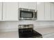 Modern kitchen boasting stainless steel microwave and stovetop, complemented by sleek white cabinets at 1031 Wisteria Way, Dundee, FL 33838