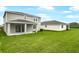 Large backyard with well-maintained lawn, patio, and an overview of the house and surroundings at 1035 Wisteria Way, Dundee, FL 33838