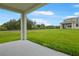 A covered patio with a green lawn and a view of the neighboring house at 1039 Wisteria Way, Dundee, FL 33838