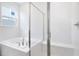 Bright bathroom featuring a soaking tub with tile surround and a glass-enclosed shower at 1039 Wisteria Way, Dundee, FL 33838