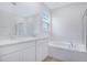 Bathroom featuring double sink vanity, soaking tub, and glass-enclosed shower at 1039 Wisteria Way, Dundee, FL 33838