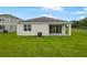 A house from the backyard with a covered patio and a green lawn at 1039 Wisteria Way, Dundee, FL 33838