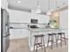 Modern kitchen featuring white cabinets, stainless steel appliances, center island with bar stools and pendant lighting at 1039 Wisteria Way, Dundee, FL 33838