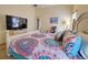 Bedroom featuring a queen bed with colorful patterned comforter, white furniture, and a mounted flat screen TV at 1047 Clear Creek Cir, Clermont, FL 34714