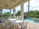 View of an outdoor dining table under a covered patio, showcasing the pool and surrounding greenery at 1057 Castle Pines Ct, Reunion, FL 34747