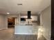 Bright kitchen features white cabinets, quartz counters, and a modern black range hood, seamlessly flowing into the living area at 1085 Whitewood Dr, Deltona, FL 32725