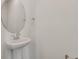 A compact half bathroom featuring a white pedestal sink, oval mirror, and chrome fixtures at 1118 Olivine Ave, Dundee, FL 33838