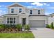 Two-story home with gray siding, stone accents, manicured lawn, and an attached two-car garage in a suburban neighborhood at 1118 Olivine Ave, Dundee, FL 33838