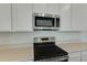 Close up on stainless steel appliances, white cabinets, and quartz countertops in a well lit, modern kitchen at 1118 Olivine Ave, Dundee, FL 33838