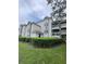 A ground-level view of the condos featuring a patio or balcony, neutral siding, and manicured hedges at 14049 Fairway Island Dr # 122, Orlando, FL 32837