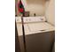 White washing machine and dryer in a compact laundry room with storage shelf at 14049 Fairway Island Dr # 127, Orlando, FL 32837