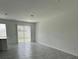 Spacious living room has grey tile floors, neutral walls, and vertical blinds on the sliding door at 2414 Skyline Loop, Kissimmee, FL 34758